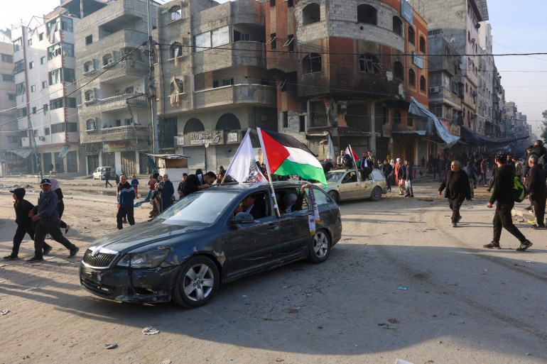 People ride in a car adroned with a Palestinian flag along a street in Gaza City on January 19, 2025, following the ceasefire deal in the Israel-Hamas war. A long-awaited ceasefire in the Israel-Hamas war was delayed January 19 after Prime Minister Benjamin Netanyahu said at the last minute that it would not take effect until the Palestinian militant group provided a list of the hostages to be released. (Photo by Omar AL-QATTAA / AFP)