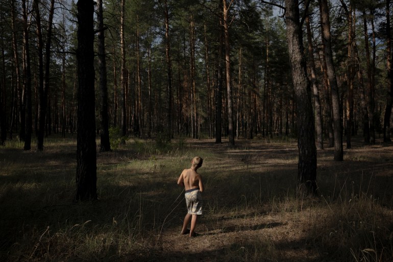 Oleksandr Fomenko, 8, stands in one of the few sections of his native forest that hasn't been mined and is accessible for mushroom picking, near Yarova, Sviati Hory national park, Donetsk region, amid Russia's attack on Ukraine, July 28, 2024. About 425,000 hectares of forest across the country have been found to be contaminated by mines and unexploded ordnance, an area half the size of Cyprus, according to the environment ministry. The damage to forests is part of a broader trail of environmental destruction caused by the war, which could leave a bleak natural legacy for decades to come, having poisoned earth and rivers, polluted the air and left vast tracts of the country riddled with mines, according to the experts. "I lived here all my life. My parents lived here, my grandmother lived here," Oleksandr's grandmother Zhenia, 49, said. "I always knew where the mushrooms would grow. But now, I don't. We can only go to places that have been demined." REUTERS/Thomas Peter SEARCH "PETER UKRAINE FORESTS" FOR THIS STORY. SEARCH "WIDER IMAGE" FOR ALL STORIES.