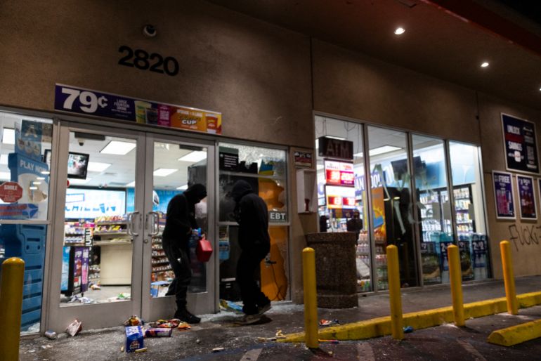 TOPSHOT - Looters break into a gas station’s market place as demonstrators and law enforcement clash with demonstrators during a protest following federal immigration operations, in the Compton neighborhood of Los Angeles, California early on June 8, 2025.