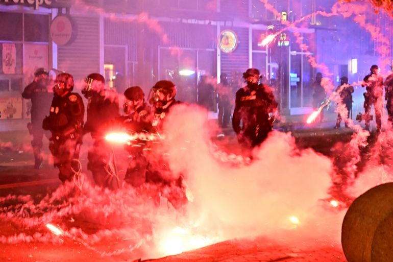 Fireworks explode around police officers in riot gear during a protest in response to federal immigration operations in the Little Tokyo neighborhood of downtown Los Angeles, on June 9, 2025.