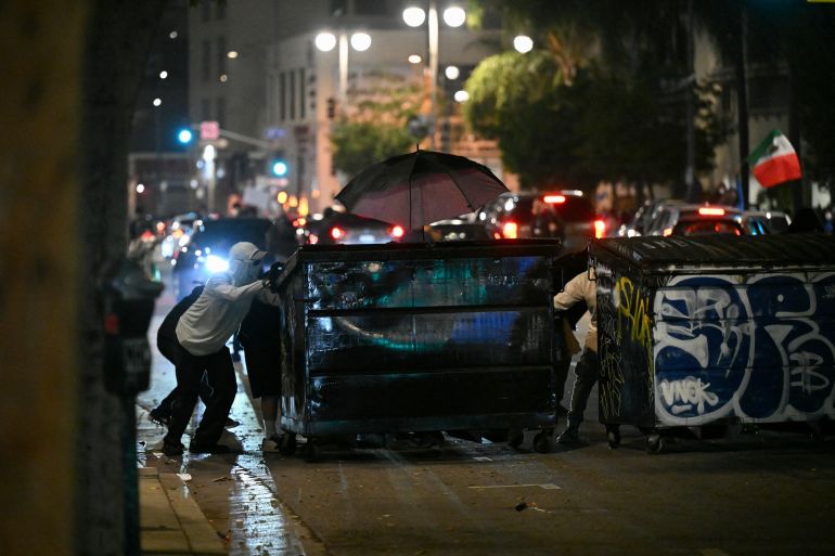 Protesters push trash bins into the street during a protest in response to federal immigration operations in the Little Tokyo neighborhood of downtown Los Angeles, on June 9, 2025.