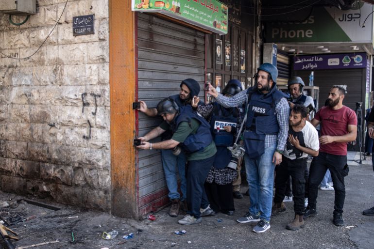 Palestinian journalists take cover after a man was shot dead by Israeli forces during a large-scale military raid in the old town of Nablus city in the occupied West Bank on June 10, 2025.