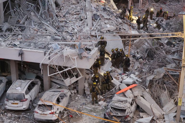 Responders work amid building rubble following a strike by an Iranian missile in the Israeli city of Bat Yam, south of Tel Aviv, early on June 15, 2025.