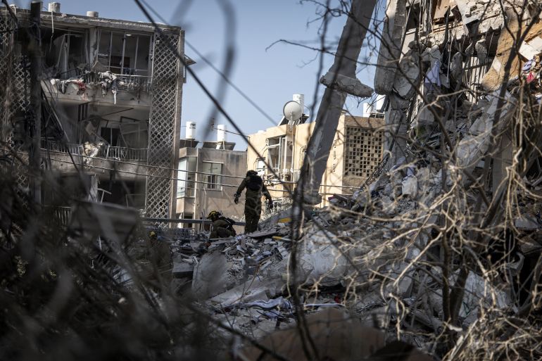 Israeli emergency responders search for victims amid the rubble of a damaged building following an overnight Iranian missile strike in Bat Yam on June 15, 2025.
