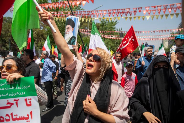 TEHRAN, IRAN - JUNE 20: Demonstrators wave Iranian flags as one holds up a poster of Iran's Supreme Leader Ayatollah Ali Khamenei during a protest against Israeli attacks on Iran, after the Friday prayer ceremonies on June 20, 2025 in central Tehran, Iran. Over recent days, Iran has been hit by a series of Israeli airstrikes targeting military and nuclear sites, as well as top military officials, prompting Iran to launch a counterattack. (Photo by Majid Saeedi/Getty Images)