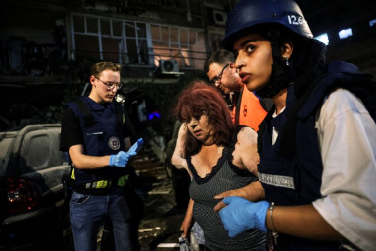 Rescue personnel help an injured woman at an impact site following missile attack from Iran on Israel, at central Israel June 15, 2025. REUTERS/Tomer Appelbaum ISRAEL OUT. NO COMMERCIAL OR EDITORIAL SALES IN ISRAEL