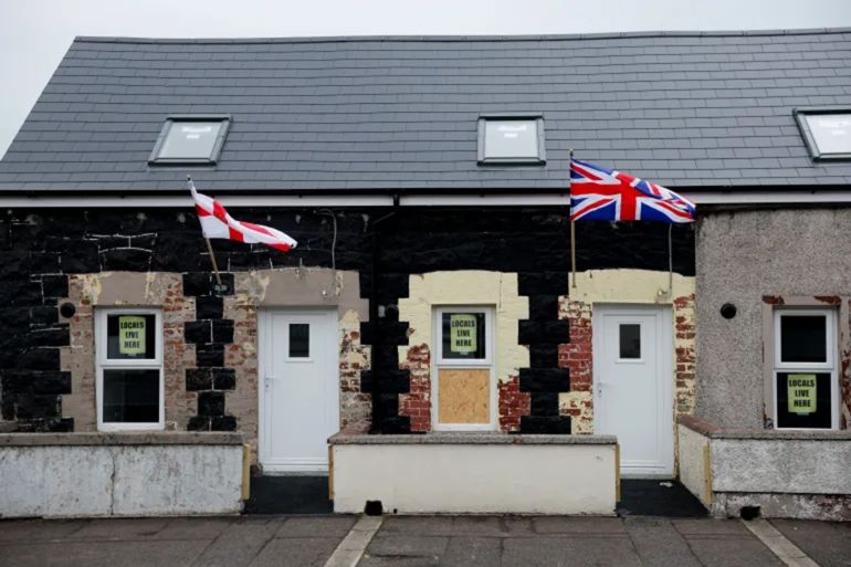 Signs reading ‘Locals live here’ are displayed following a protest over an alleged sexual assault on a local teenage girl, in Ballymena, Northern Ireland, June 12, 2025 [Clodagh Kilcoyne/Reuters]