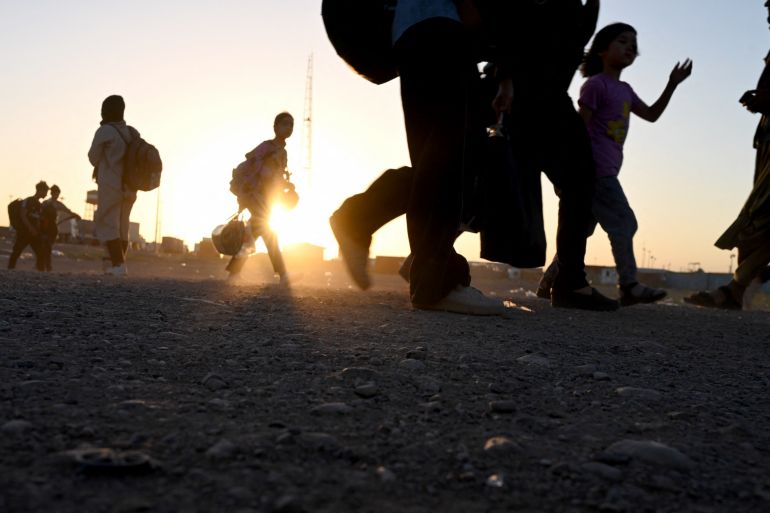 Afghan refugees carrying their belongings as they arrive at the zero point of the Islam Qala border crossing between Afghanistan and Iran on June 28, 2025, following their deportation from Iran.
