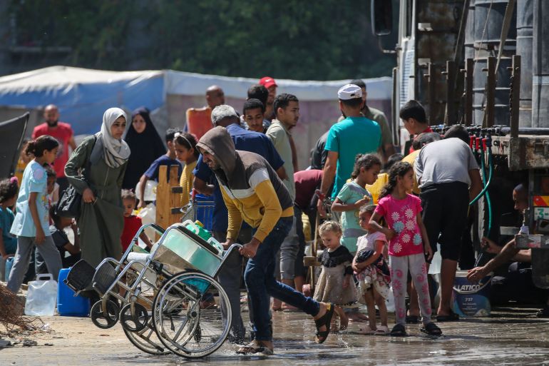 Palestinians gather to fill their containers with water in the Nuseirat camp for refugees in the central Gaza Strip on May 24, 2025.