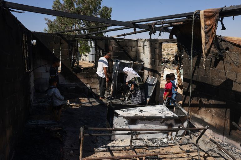 Palestinians Nasser Ishreiteh, his mother Fawzyah and his children clear burnt belongings in the living and kitchen area of their house after a reported attack overnight by Israelis from a nearby settlement, in Susya south of Hebron city in the occupied West Bank on June 25, 2025.