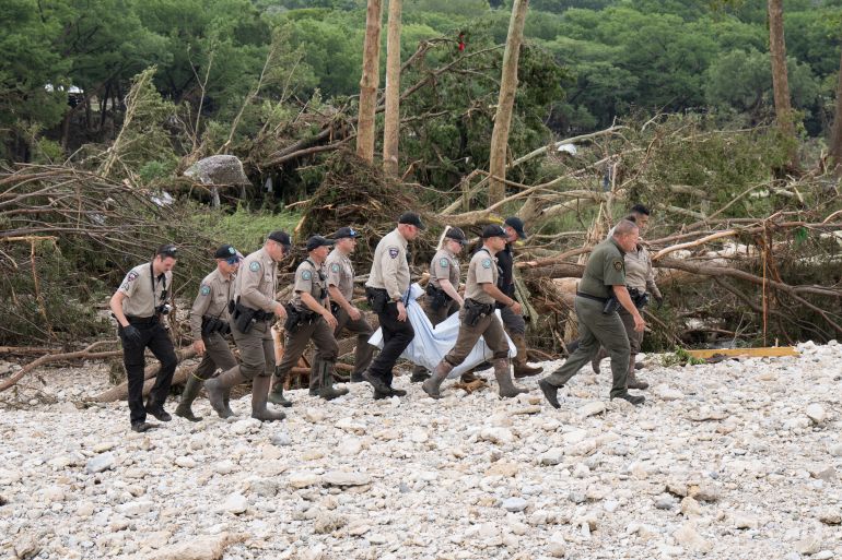 HUNT, TEXAS - JULY 05: Texas Game Wardens and local law enforcement carry the body of a flood victim from the banks of the Guadalupe River during recovery operations on July 5, 2025 near Hunt, Texas. Heavy rainfall caused flooding along the Guadalupe River in central Texas with at least 43 fatalities reported. Eric Vryn/Getty Images/AFP (Photo by Eric Vryn / GETTY IMAGES NORTH AMERICA / Getty Images via AFP)