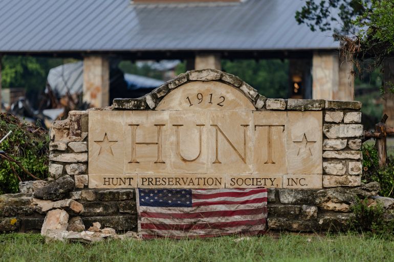 HUNT, TEXAS - JULY 6: An American flag hangs in front of the city sign after flash flooding tore through the area on July 6, 2025 in Hunt, Texas. Heavy rainfall caused flooding along the Guadalupe River in central Texas with multiple fatalities reported. Jim Vondruska/Getty Images/AFP (Photo by Jim Vondruska / GETTY IMAGES NORTH AMERICA / Getty Images via AFP)