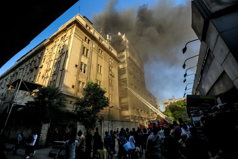People look on as firefighters douse the flames after a fire broke out in the Telephones landline exchanging station and Ministry of Communications building in the heart of Cairo on July 7, 2025.