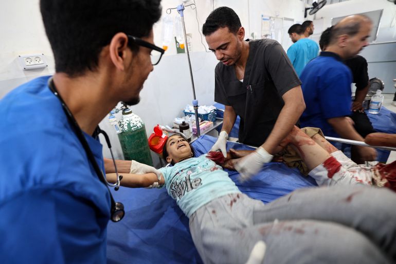 TOPSHOT - A Palestinian girl reacts as she receives treatment for her injuries at the Al-Awda hospital in Nuseirat in the central Gaza Strip, following Israeli strikes on July 13, 2025.