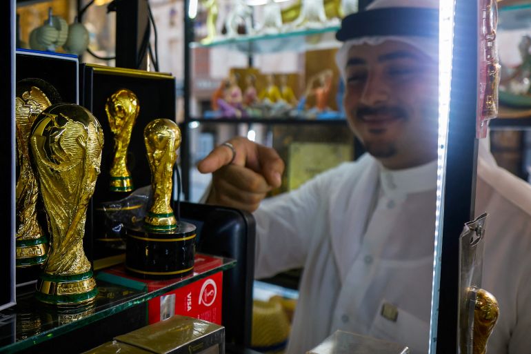 A man points to a replica of the Qatar 2022 World Cup trophy at a gift shop in Souq Waqif bazaar in Doha on July 24, 2025. (Photo by Karim JAAFAR / AFP)
