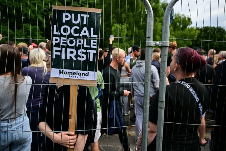A protestor holds a placard reading "Put local first" during a an anti-immigrant demonstration outside The Bell Hotel believed to be housing asylum seekers, in Epping, northest of London, on July 27, 2025, after police charged an asylum-seeker with sexual offences earlier this month.