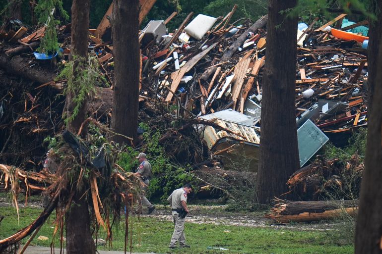 Officials comb through the banks of the Guadalupe River after a flash flood swept through the area Saturday, July 5, 2025, in Hunt, Texas. (AP Photo/Julio Cortez)