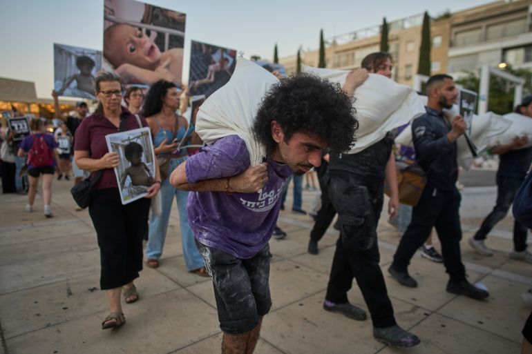 Israeli activists take part in a protest against the war in the Gaza Strip, Israel's measures regarding food distribution and the forced displacement of Palestinians, in Tel Aviv, Israel, Tuesday, July 22, 2025. (AP Photo/Ohad Zwigenberg)