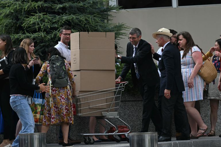 A fired US State Department worker pushes his belongings in a shopping cart as he leaves the building in Washington, DC, on July 11, 2025. The US State Department began laying off more than 1,300 employees as part of President Donald Trump's campaign to massively downsize the federal government workforce. A State Department official said 1,107 members of the civil service and 246 Foreign Service employees were being informed that they were being fired. (Photo by SAUL LOEB / AFP)