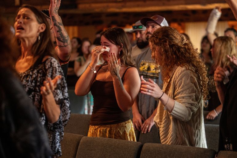 A woman reacts as churchgoers sing worship songs at a service following deadly flooding in Kerrville, Texas, U.S., July 6, 2025. REUTERS/Sergio Flores
