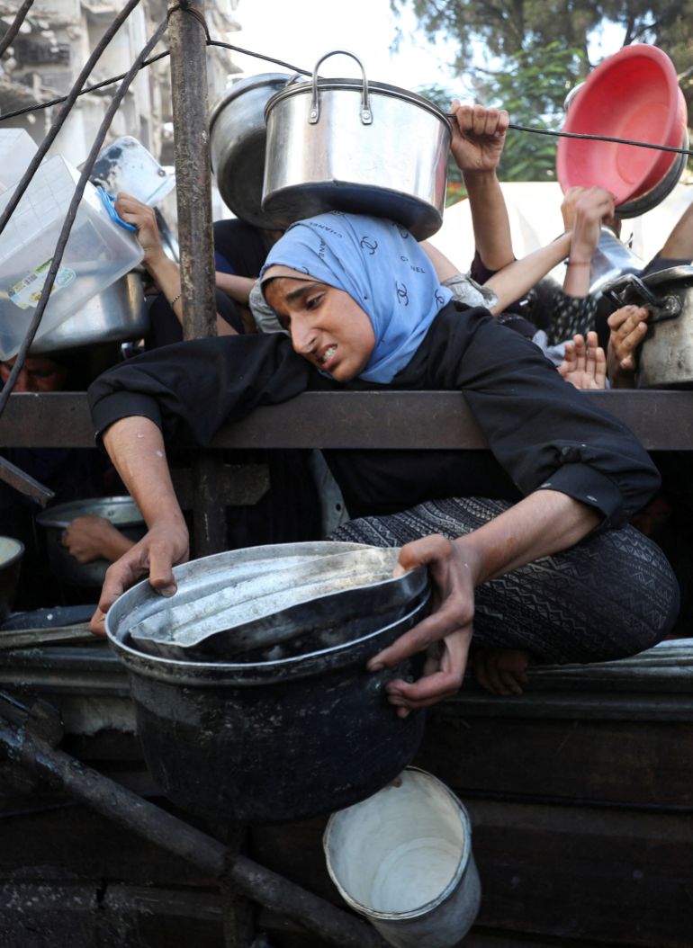 A Palestinian woman reacts as she asks for food from a charity kitchen, amid a hunger crisis, in Gaza City, July 14, 2025. REUTERS/Mahmoud Issa