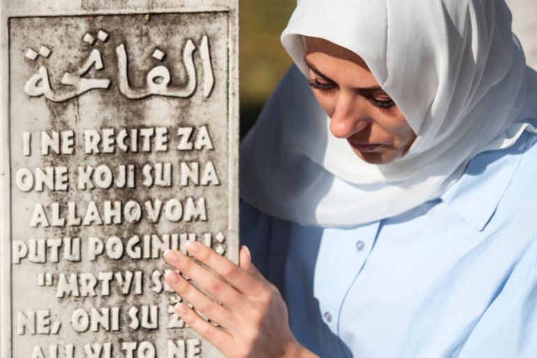 A Bosnian Muslim woman looks at the details of a grave stone amid others, of victims killed during the Srebrenica genocide, at the Srebrenica Genocide Memorial in Potocari, Bosnia and Herzegovina, July 11, 2025. REUTERS/Amel Emric