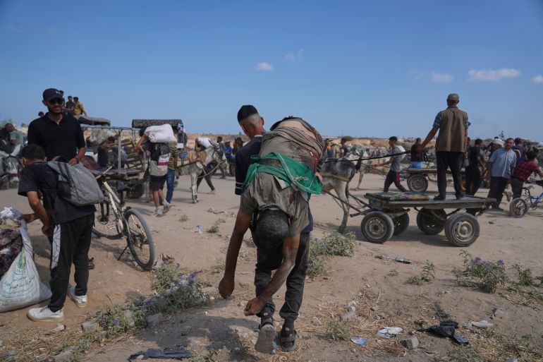 A Palestinian carries the body of a man killed while trying to receive aid near a distribution center operated by the U.S.-backed Gaza Humanitarian Foundation (GHF) in Netzarim, in the Gaza Strip, Aug. 4, 2025. (AP Photo/Abdel Kareem Hana)