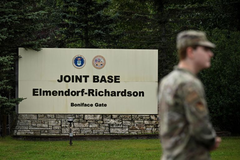 A member of the military stands outside an entrance to Joint Base Elmendorf-Richardson in Anchorage, Alaska, on August 14, 2025, ahead of the August 15 scheduled meeting between US President Donald Trump and Russian President Vladimir Putin. Trump on Thursday acknowledged his high-stakes summit with Vladimir Putin may fail, and said any Ukraine deal would come through a future three-way meeting with Kyiv to "divvy things up." Russian President Vladimir Putin flies to Alaska on Friday at the invitation of Trump in his first visit to a Western country since he ordered the 2022 invasion of Ukraine that has killed tens of thousands of people. (Photo by Drew ANGERER / AFP)