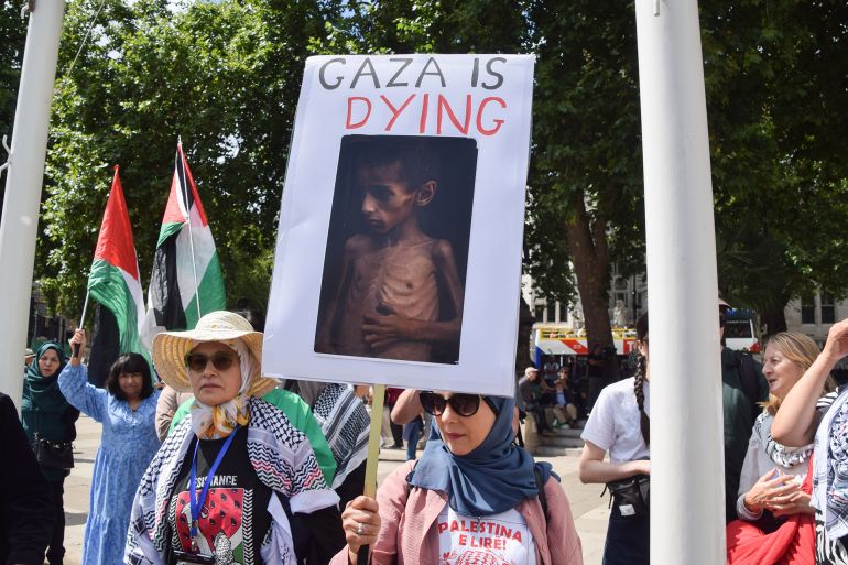 LONDON, UNITED KINGDOM - 2025/08/09: A protester holds a placard depicting a starving child in Gaza during the demonstration in Parliament Square. Hundreds of people gathered to show support for the activist group Palestine Action, which has been banned under anti-terrorism law. (Photo by Vuk Valcic/SOPA Images/LightRocket via Getty Images)