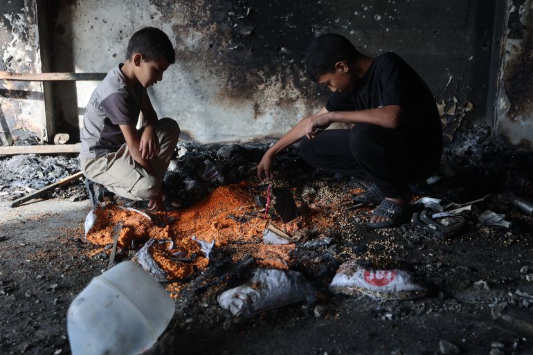 Palestinian youths site next to burnt sacks of grain as they check the damage after an Israeli airstrike hit the Mussa bin Nusseir UNRWA school, serving as a shelter for people who left their homes in the besieged Palestinian territory, in Gaza City's Daraj district on May 20, 2025.