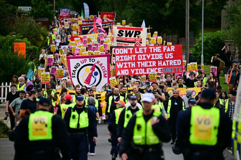 Protestors hold a banner reading "Don't let the far right divide us with their hatred and violence: unite" as they march from Epping station towards The Bell Hotel believed to be housing asylum seekers, in Epping, northest of London, on July 27, 2025 to protest against the anti-immigrant demonstrations of the past few days.