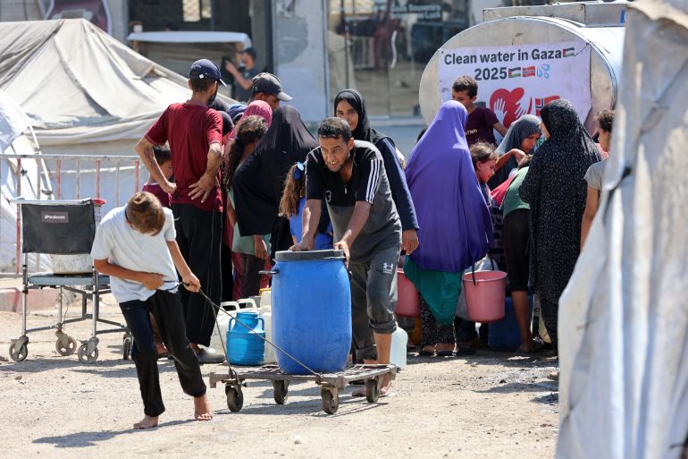 Palestinians transport gallons of clean water from a distribution point in Gaza City on August 1, 2025. (Photo by Omar AL-QATTAA / AFP)