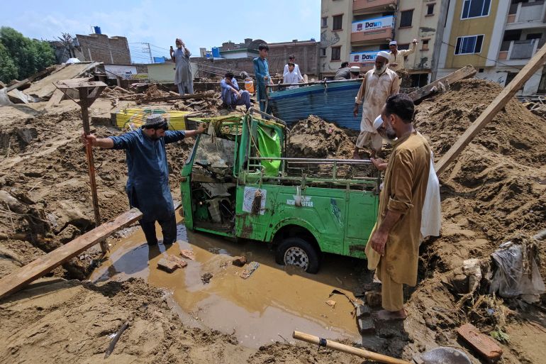 Local residents remove mud to recover an auto rickshaw from debris after Friday's flash flooding, in Mingora, the main town of Swat Valley, in Pakistan's northwest, Saturday, Aug. 16, 2025. (AP Photo/Sherin Zada)