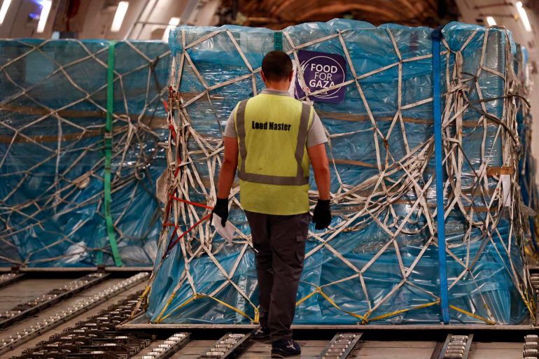 epa12289373 A worker stands next to boxes with humanitarian aid from the 'Food for Gaza' initiative during preparations for shipment in a transport aircraft at Fiumicino Airport, in Rome, Italy, 08 August 2025. EPA/FABIO FRUSTACI