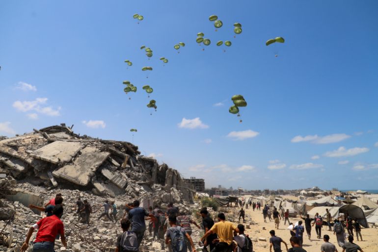 Palestinians run towards parachutes carrying aid packages airdropped over northern Gaza Strip, August 7, 2025. REUTERS/Ebrahim Hajjaj