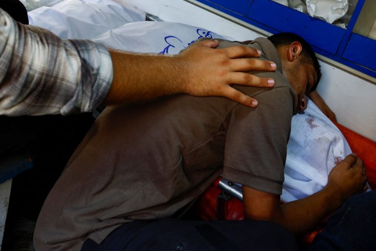 A Palestinian man reacts over the body of Al Jazeera journalist Anas Al Sharif, who was killed along with four colleagues in an Israeli airstrike, inside an ambulance in Gaza City August 11, 2025. REUTERS/Mahmoud Issa REFILE - QUALITY REPEAT