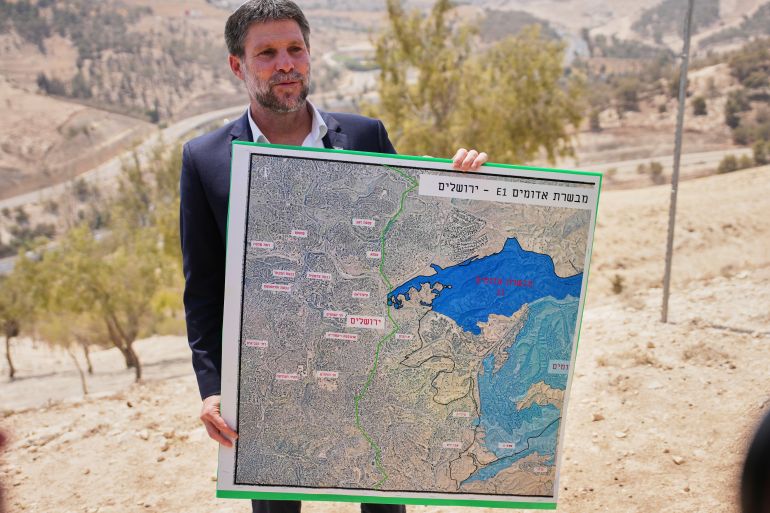 Israeli Finance Minister Bezalel Smotrich holds a map that shows the E1 settlement project during a press conference near the settlement of Maale Adumim, in the Israeli-occupied West Bank, Wednesday, Aug. 14, 2025. (AP Photo/Ohad Zwigenberg)