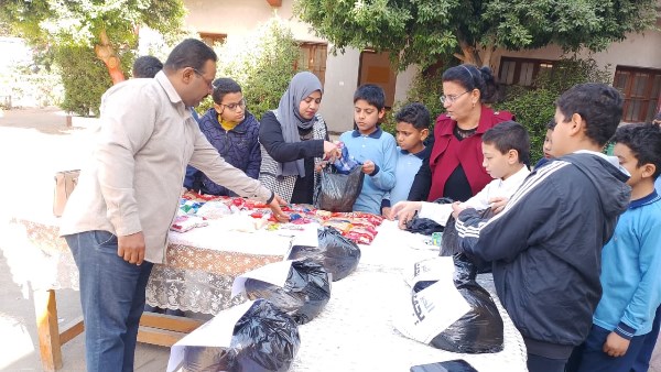 تلاميذ مدرسة أرمنت الابتدائية يشاركون في تعبئة شنط رمضان بالأقصر